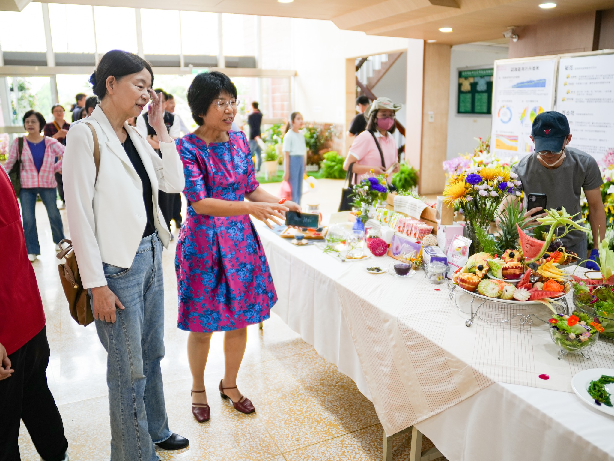 楊宏瑛場長(右)向農業部范美玲主秘(左)介紹花花世界區展示之花與飲食餐桌。