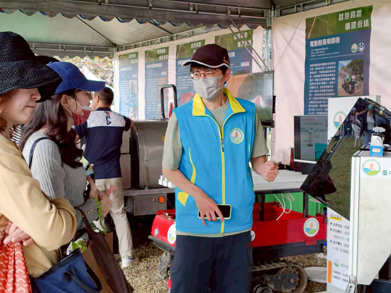 洪榆宸助理研究員向高雄農改場開放日活動觀展民眾介紹穴盤苗篩選機。