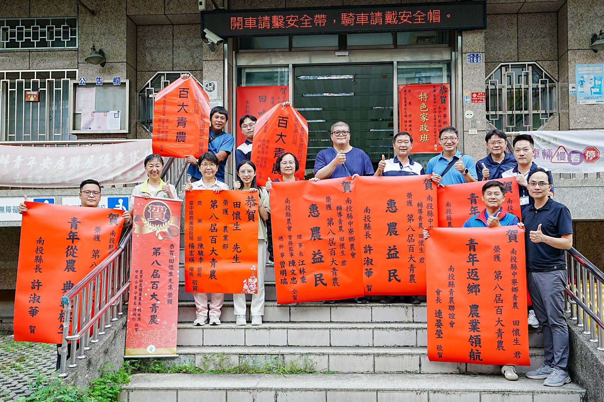 本場楊宏瑛場長(前排左3)與農業推廣科吳建銘科長(前排右1)等人前往中寮鄉會張貼紅榜,祝賀青農田懷生(中)獲選農業部第八屆百大青農殊榮。