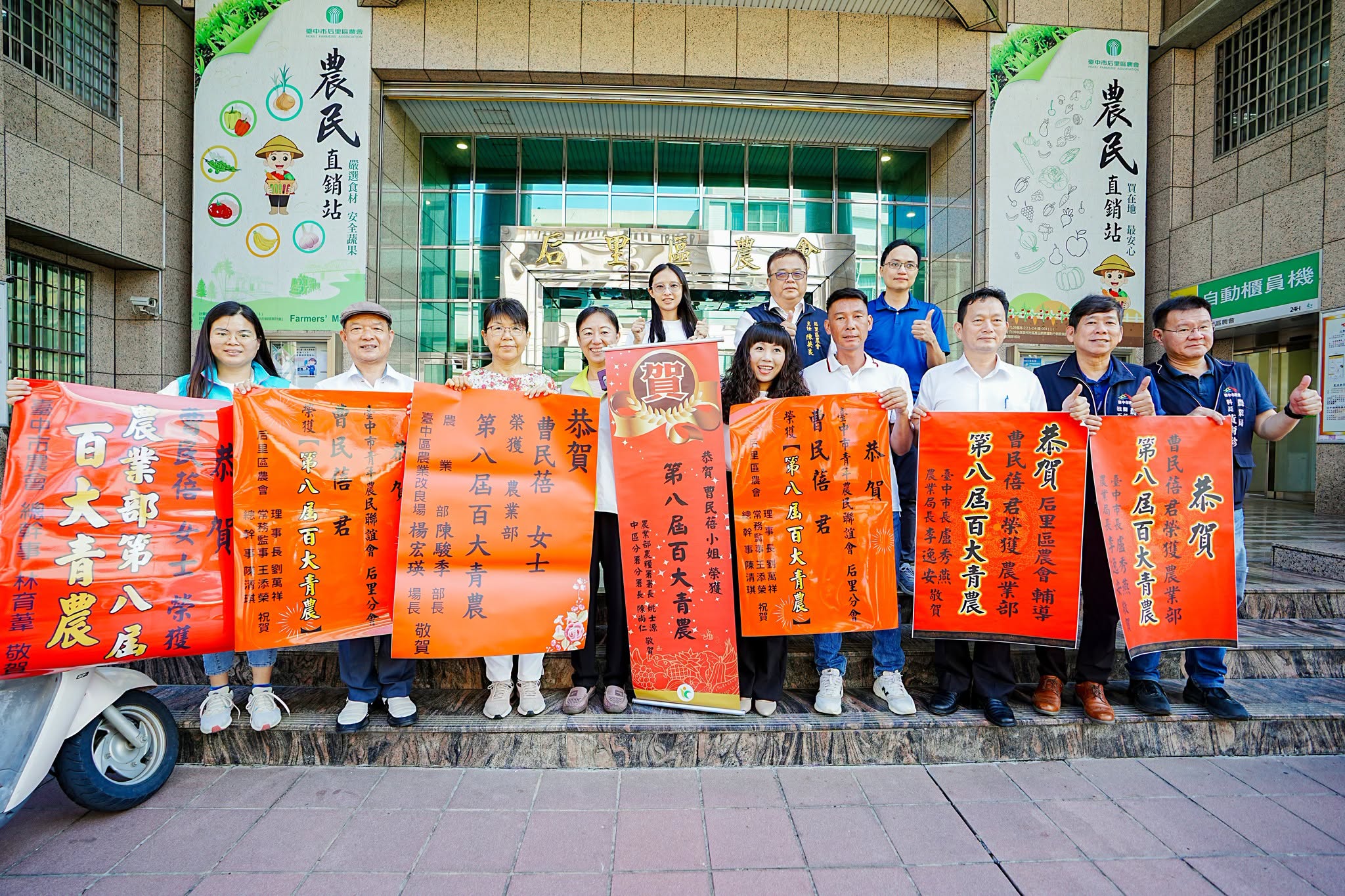本場楊宏瑛場長(前排左3)與農業推廣科吳建銘科長(後排右1)等人前往后里區農會張貼紅榜,祝賀青農曹民蓓(前排中)獲選農業部第八屆百大青農殊榮。