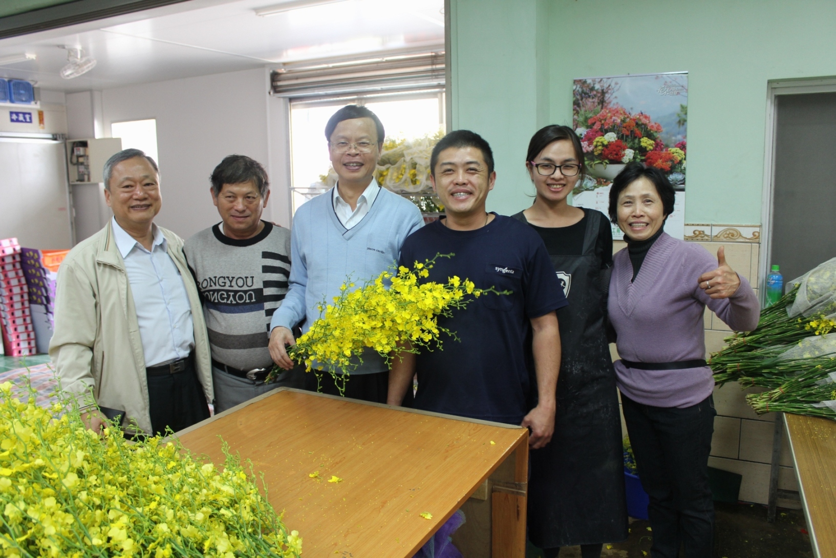 林場長與林錦宏課長拜訪新社區花卉產銷班第 7 班，關心文心蘭外銷業務，並與廖明輝班長（左二）全家合影 