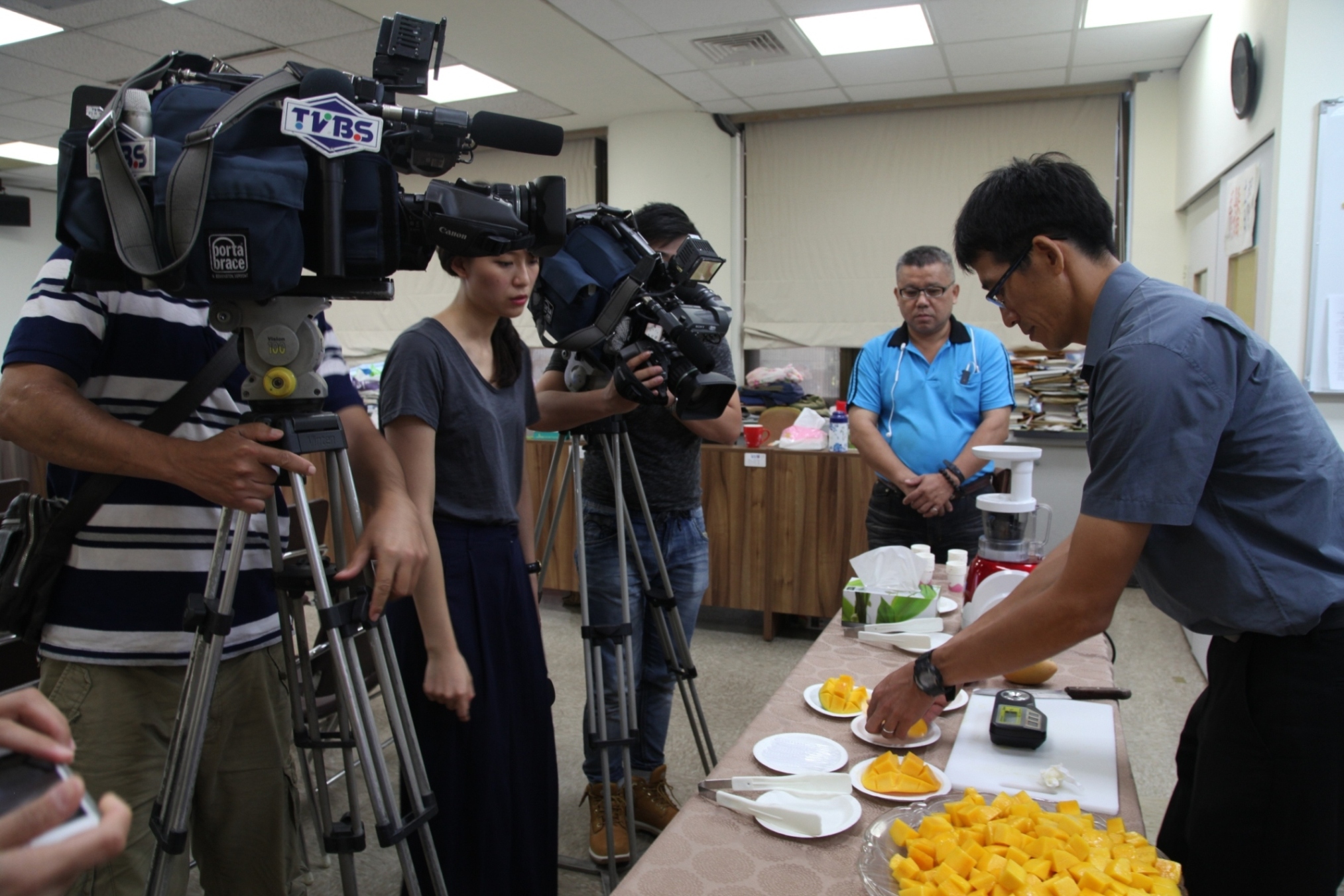 本場研究人員陳盟松先生（右一）向記者介紹「芒果臺中 1 號」糖度及果肉品質均優 